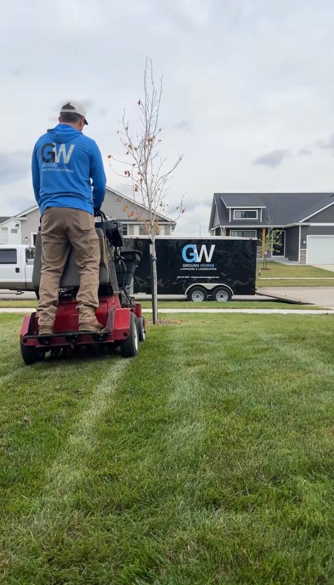 Operator on red Exmark aerator with Ground Works trailer in background